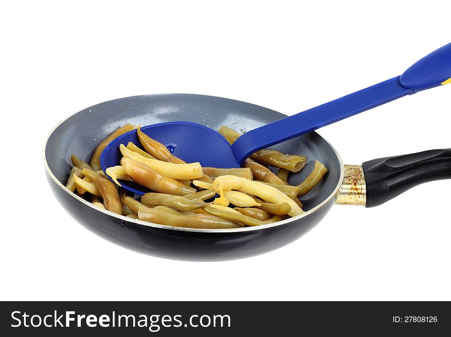 Stewed French bean on the pan with big blue spoon isolated on white background. Stewed French bean on the pan with big blue spoon isolated on white background