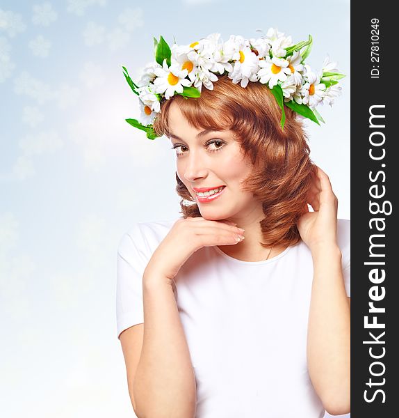 Young beautiful woman in a wreath of flowers on the abstract background