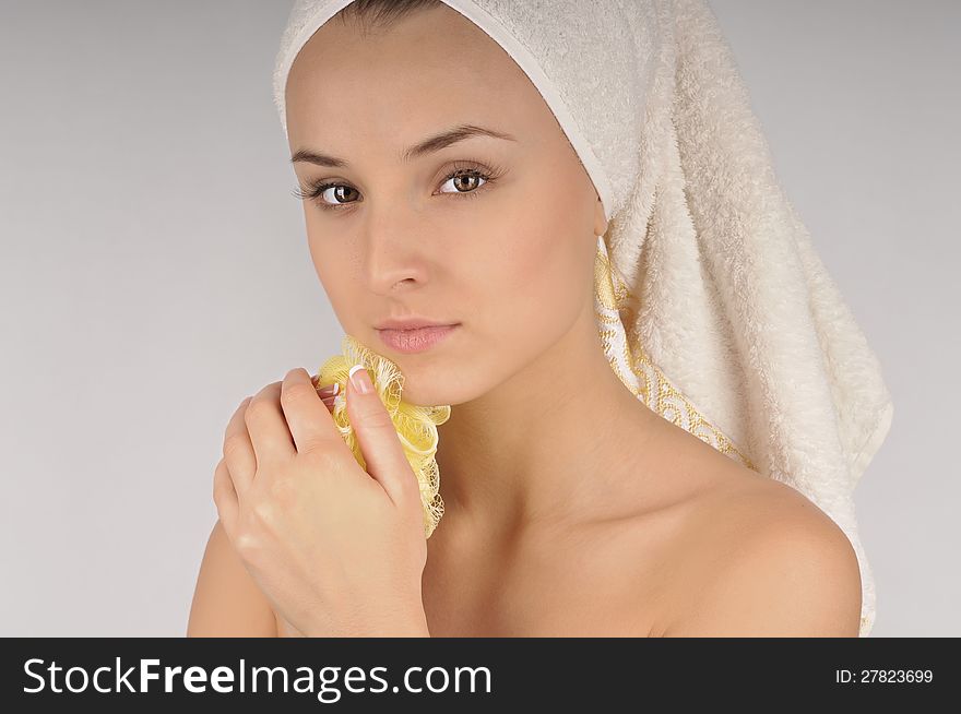 Beautiful woman in a white towel washing your neck yellow sponge. Beautiful woman in a white towel washing your neck yellow sponge