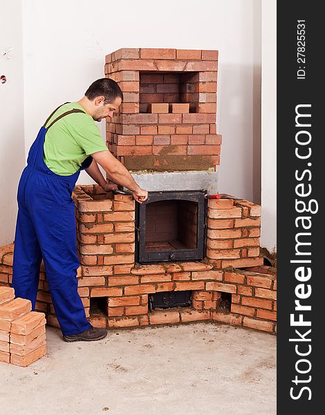 Worker mounting door to a masonry heater - half finished