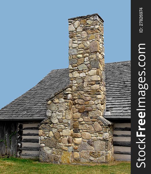 Large chimney made of field stones on the outside wall of a log cabin, against a blue sky. Large chimney made of field stones on the outside wall of a log cabin, against a blue sky.