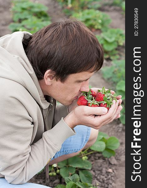 Man Holding A Strawberry And Sniffs It