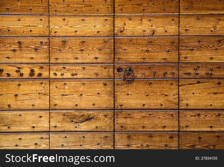 Abstract background of wooden panels studded with nails of differing sizes in rows with woodgrain texture