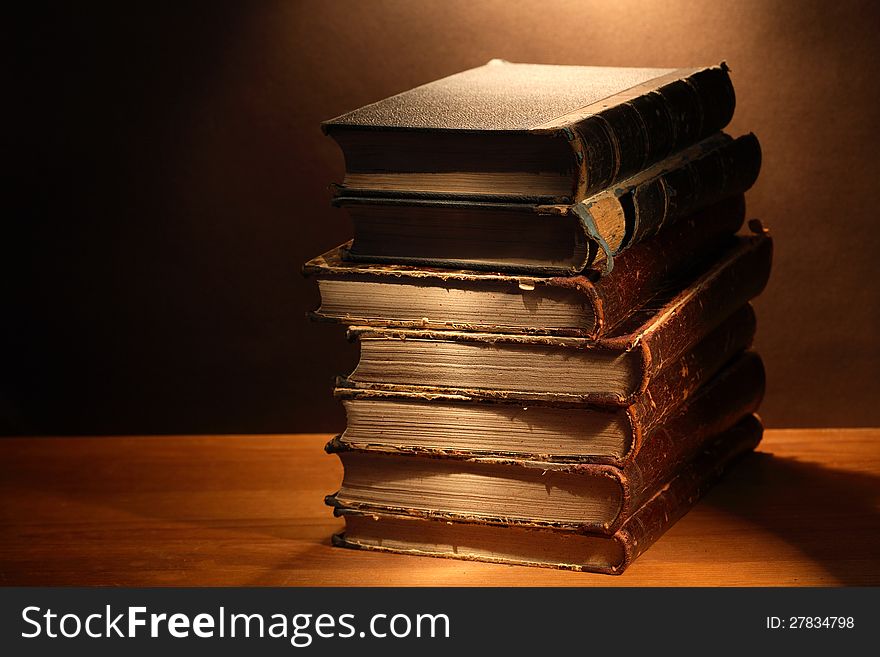 Stack of antique books on wooden surface under beam of light. Stack of antique books on wooden surface under beam of light
