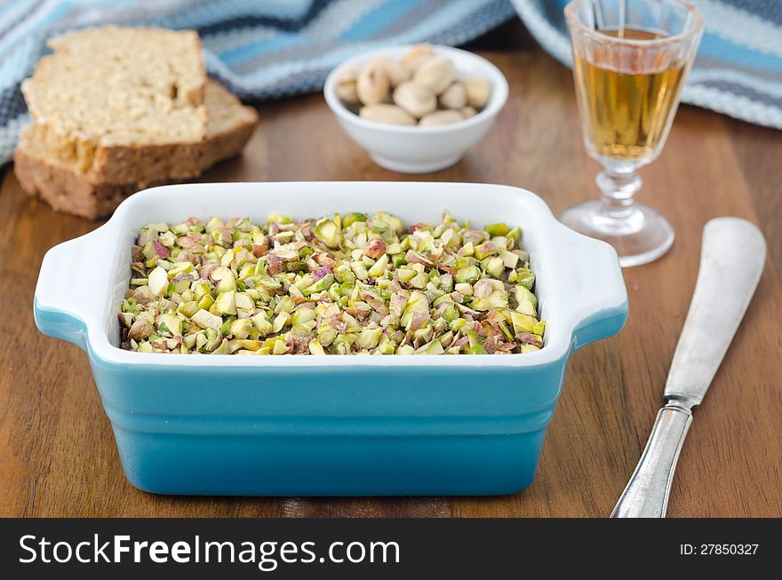 Chicken liver pate with pistachios. Bread, port wine and pistachios in the background.