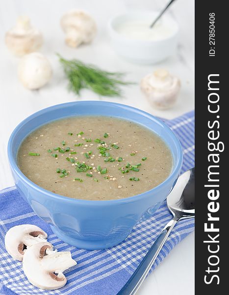 Bowl of mushroom soup with fresh mushrooms and dill close up