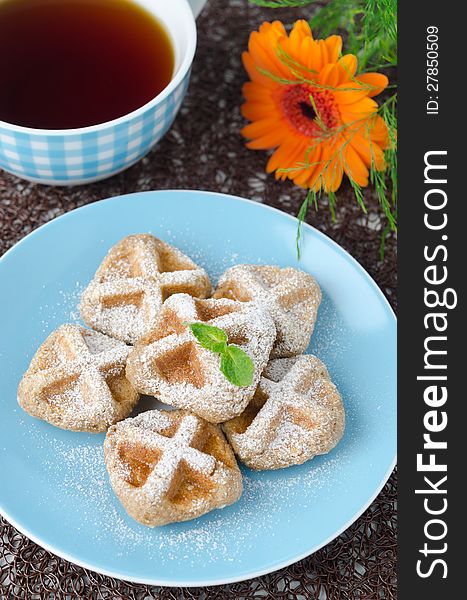 Waffles sprinkled with powdered sugar and black tea