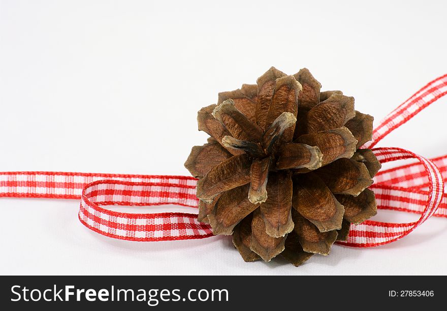 One single pine-cone decoration with red and white ribbon