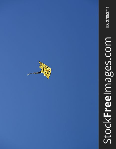 Smiling yellow kite in a cloudless sky. Smiling yellow kite in a cloudless sky