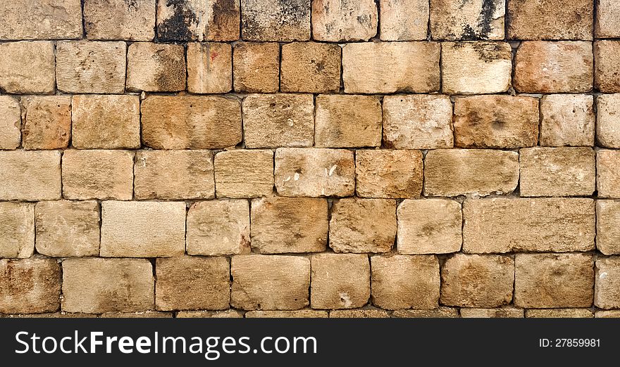 A wall made up of tiled rectangular blocks of sand stone. A wall made up of tiled rectangular blocks of sand stone