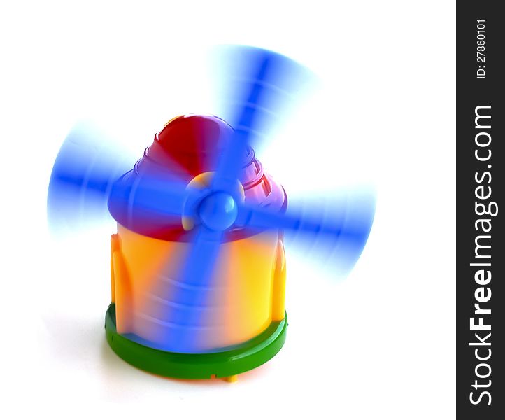 A toy wind mill with its plastic blades in motion. A toy wind mill with its plastic blades in motion