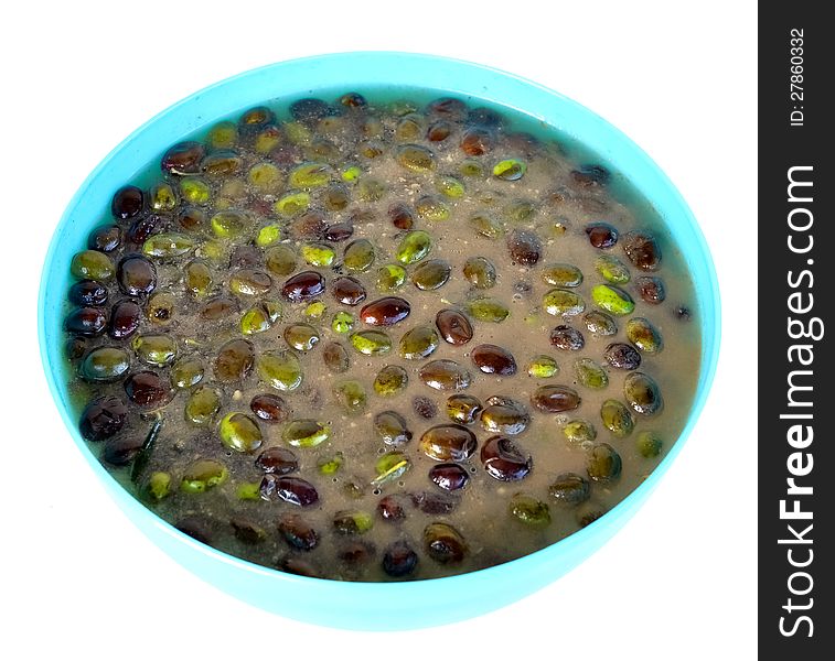 Olives being pickled with salt and water in a blue plastic container. Olives being pickled with salt and water in a blue plastic container