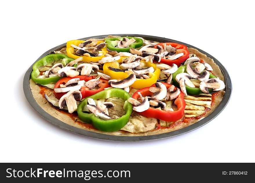 An uncooked vegetarian pizza with eggplant and zucchini slices with colorful capsicums and mushrooms. An uncooked vegetarian pizza with eggplant and zucchini slices with colorful capsicums and mushrooms