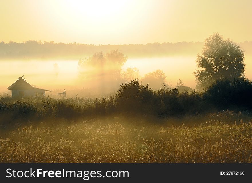 The log hut in a morning fog against the wood. The log hut in a morning fog against the wood