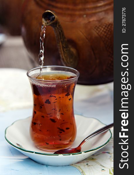 A glass of Turkish tea with tea pot