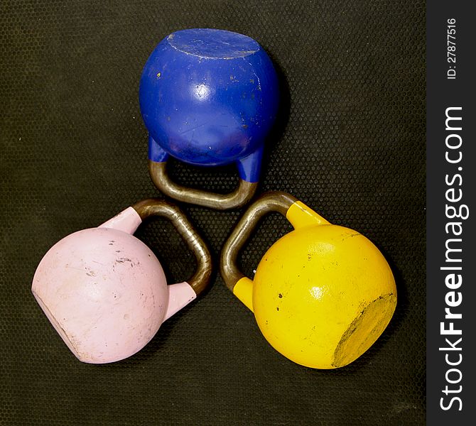 Close up photo of 3 Kettlebells on a gym floor.