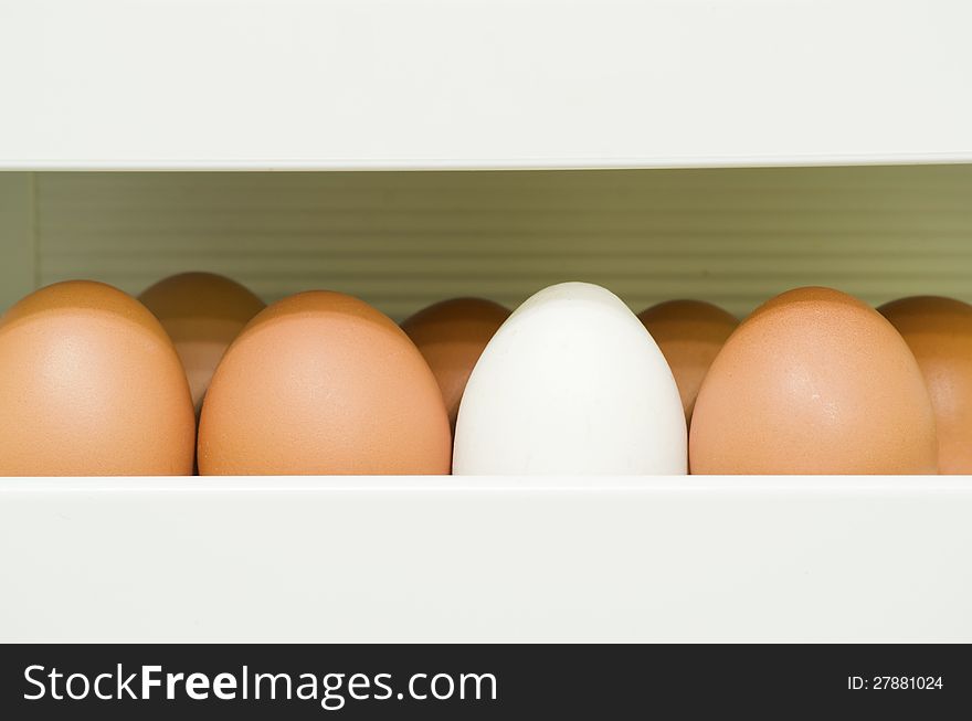 Fragment of refrigerator container full of red eggs with white one. Fragment of refrigerator container full of red eggs with white one