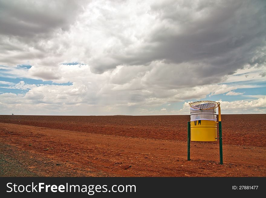 A simple low level landscape view of a red stony desert with a threatening looking sky in the background.