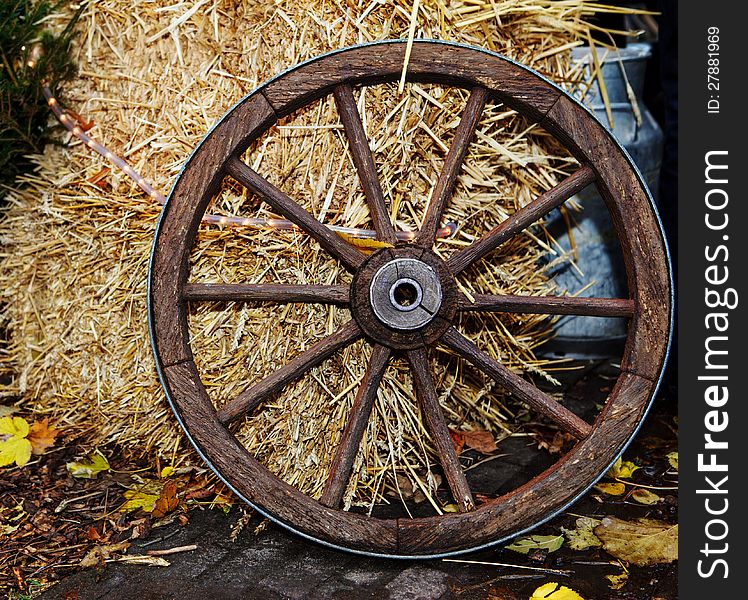 Old cartwheel standing beside hay stack