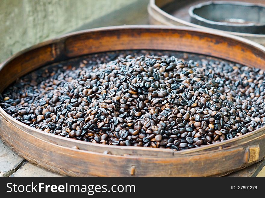 Fresh roasted coffee beans for sale in a flat round container at an outdoor market