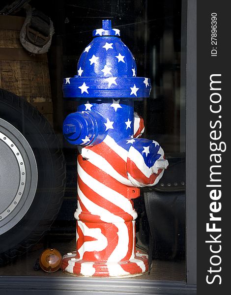 An American flag painted on a fire hydrant displayed on a store window. An American flag painted on a fire hydrant displayed on a store window.