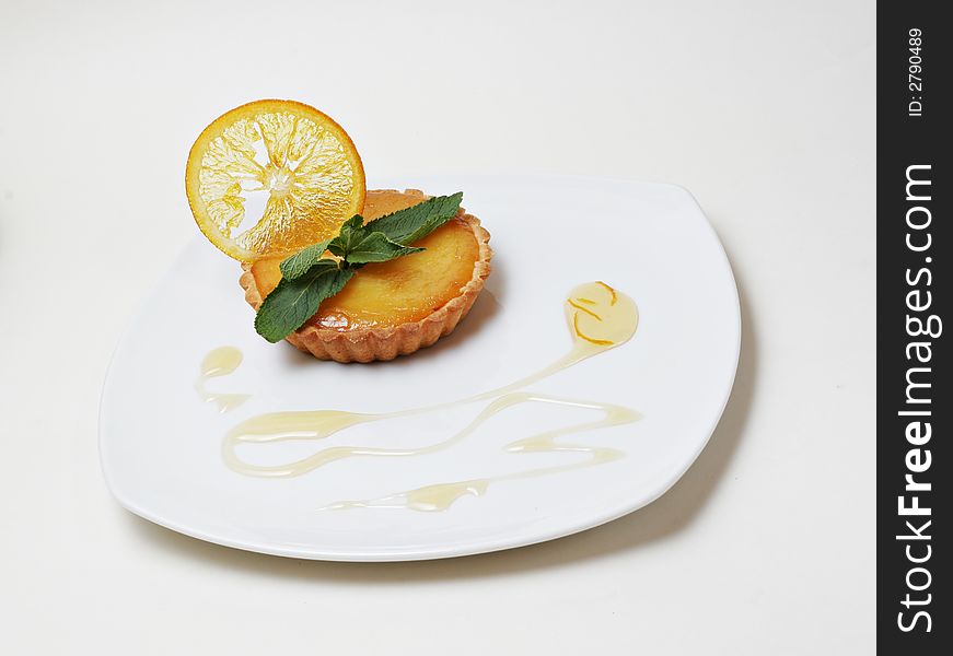 Pastry with orange slice and mint over white background