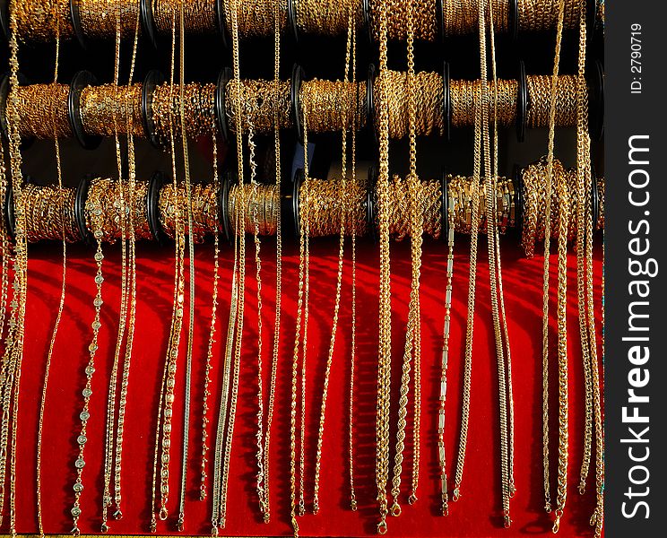 Several golden necklaces hanging on a rack in a street market