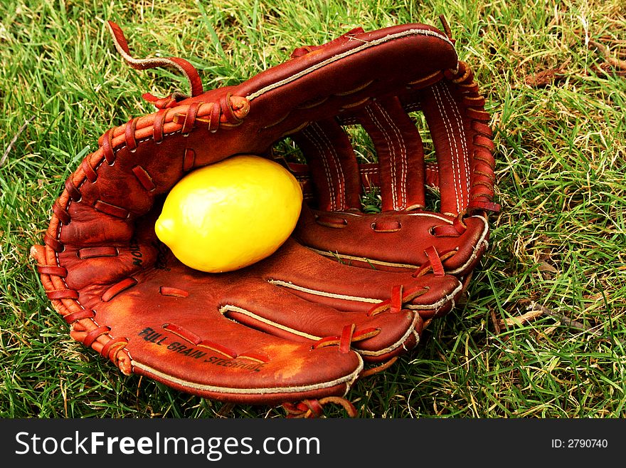 Grassy patch where an old Baseball Mitt holds a lemon inside. Grassy patch where an old Baseball Mitt holds a lemon inside