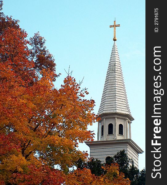 Shows a church steeple agains an eggshell blue sky flanked by brilliant fall color. Shows a church steeple agains an eggshell blue sky flanked by brilliant fall color