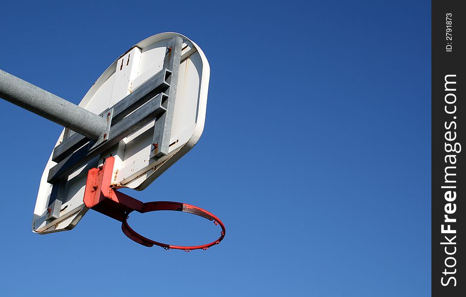 A playground basketball hoop against a blue sky. A playground basketball hoop against a blue sky.