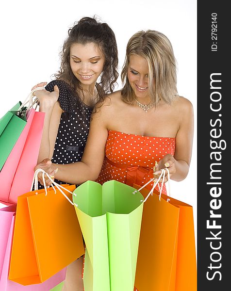 Two beautiful, young woman standing and holding bags. First woman is showing something in her's bag. Both woman are looking at bag. Two beautiful, young woman standing and holding bags. First woman is showing something in her's bag. Both woman are looking at bag.