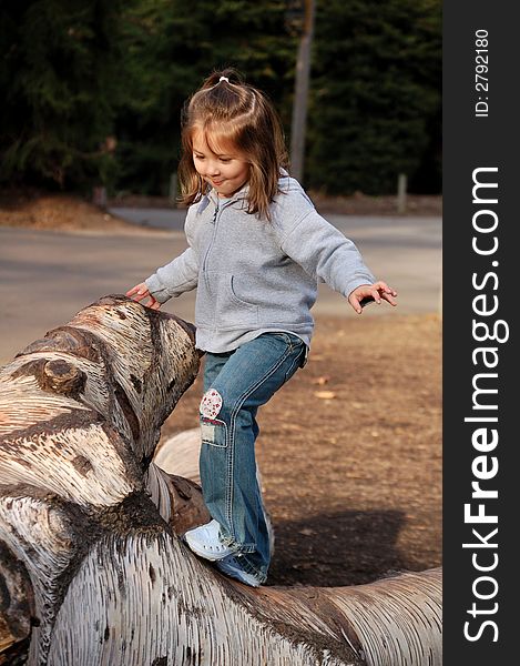 Four year old girl trying to keep her balance while walking on a tree. Four year old girl trying to keep her balance while walking on a tree.
