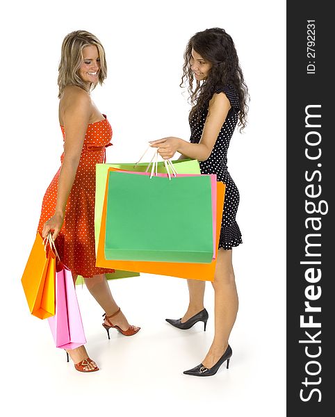 Two beautiful, young woman standing and holding bags. First woman is showing something in her's bag. Second woman looking at bag. Isolated on white in studio. Whole body. Two beautiful, young woman standing and holding bags. First woman is showing something in her's bag. Second woman looking at bag. Isolated on white in studio. Whole body