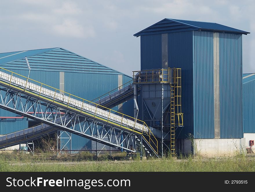 Blue warehouse buildings with walls and roofs of corrugated steel. Enclosed conveyor belts between the buildings. Blue warehouse buildings with walls and roofs of corrugated steel. Enclosed conveyor belts between the buildings.
