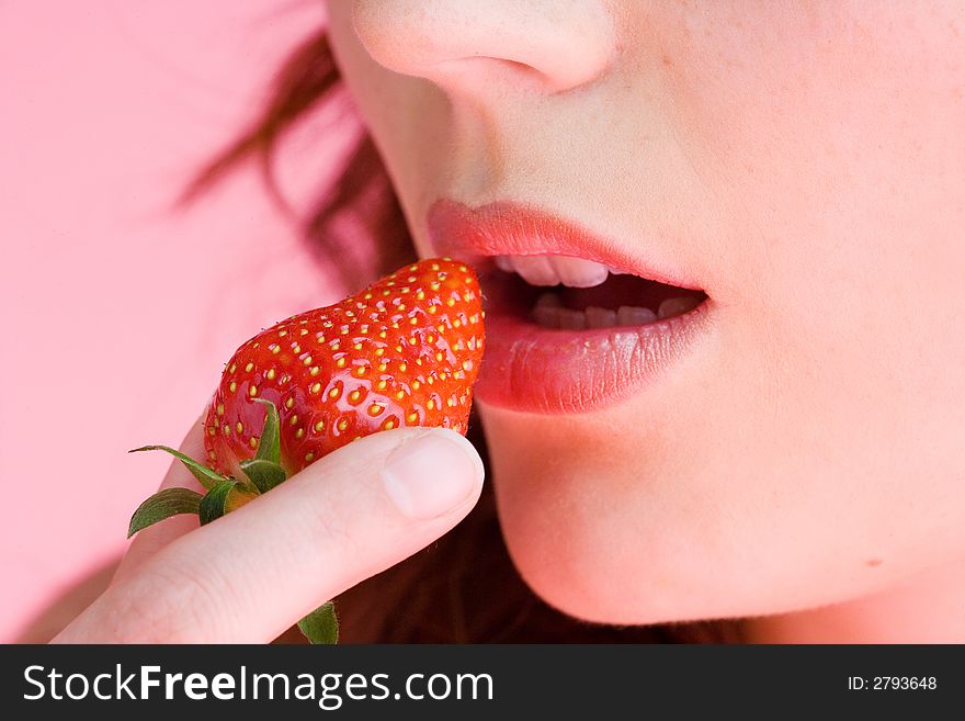 One young, beautiful woman eats a strawberry. One young, beautiful woman eats a strawberry