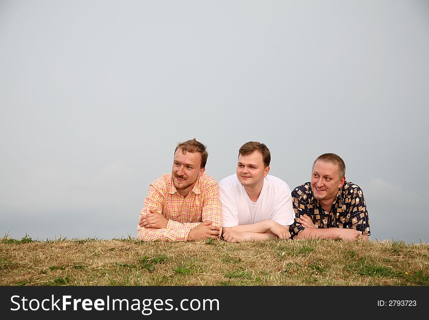 Three men, laying on the grass