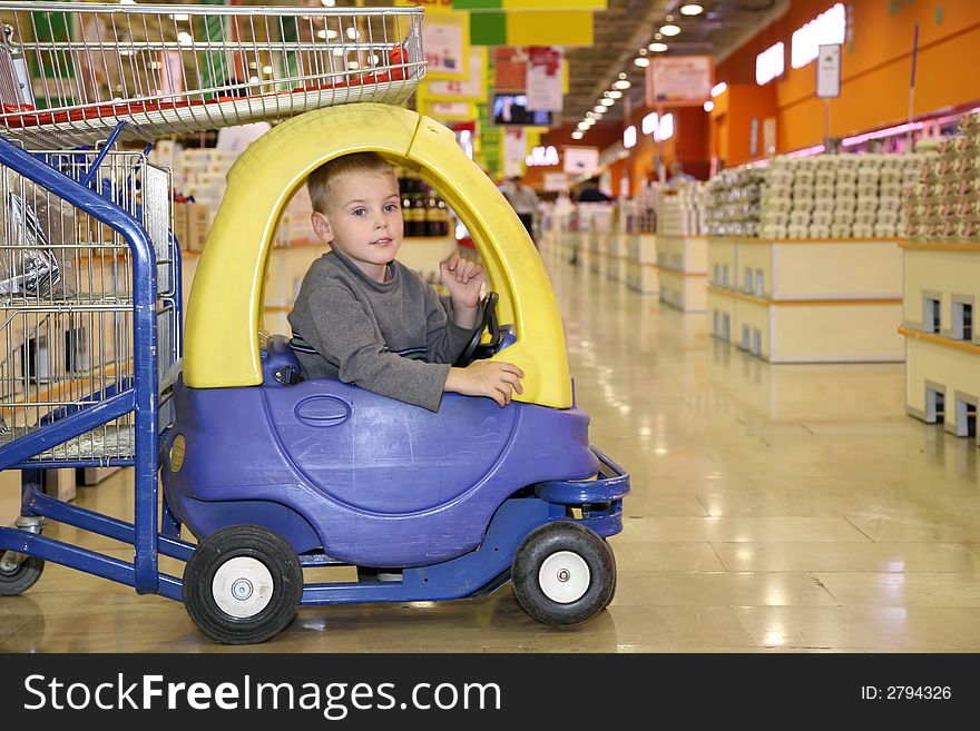 Child in the toy automobile in the supermarket