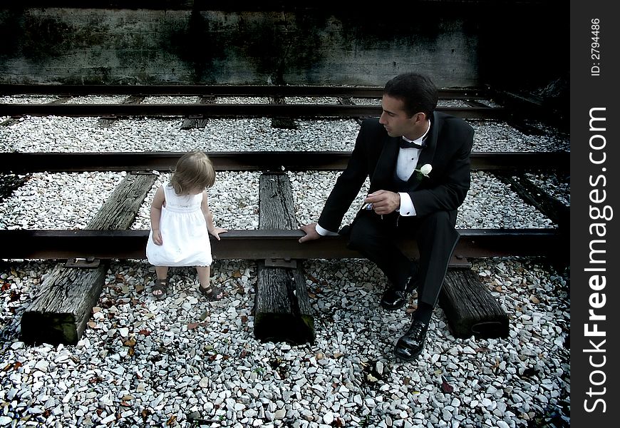 A father and daughter sitting on railroad tracks. A father and daughter sitting on railroad tracks