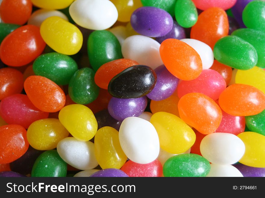 Black jellybean among all other colored jellybeans. Black jellybean among all other colored jellybeans
