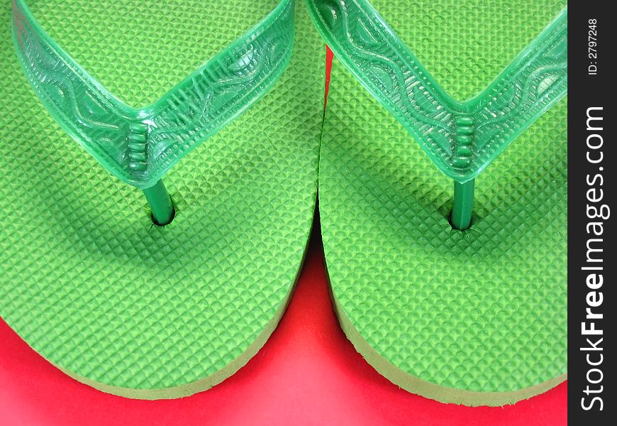 Green plastic flip flops against colored background