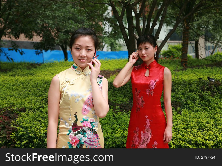 Two asian young woman stand holding cellphone. Two asian young woman stand holding cellphone