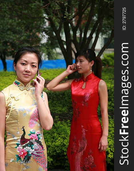 Two asian young woman stand holding cellphone. Two asian young woman stand holding cellphone