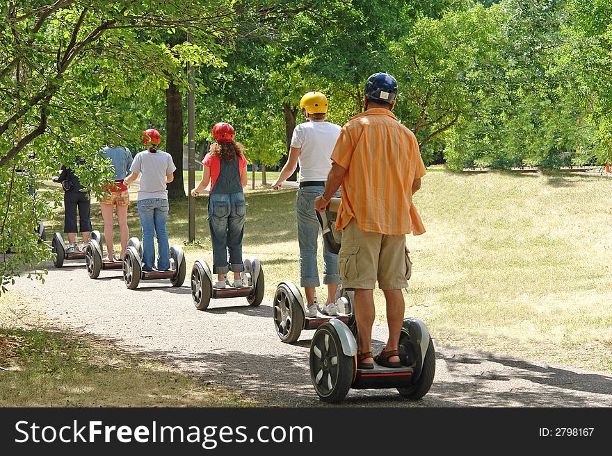 A picture of scooter riders cruising through the park on a pleasant day