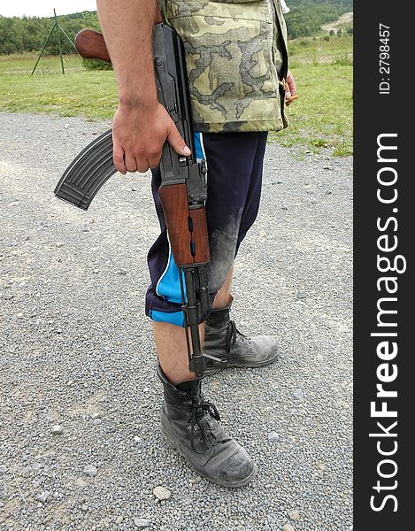 A detail of  a soldierÂ´s legs and  a machine rifle in his hand. A detail of  a soldierÂ´s legs and  a machine rifle in his hand