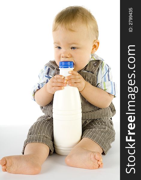 Little baby boy sitting on the floor. Holding and biting a bottle of milk. Whole body. Little baby boy sitting on the floor. Holding and biting a bottle of milk. Whole body