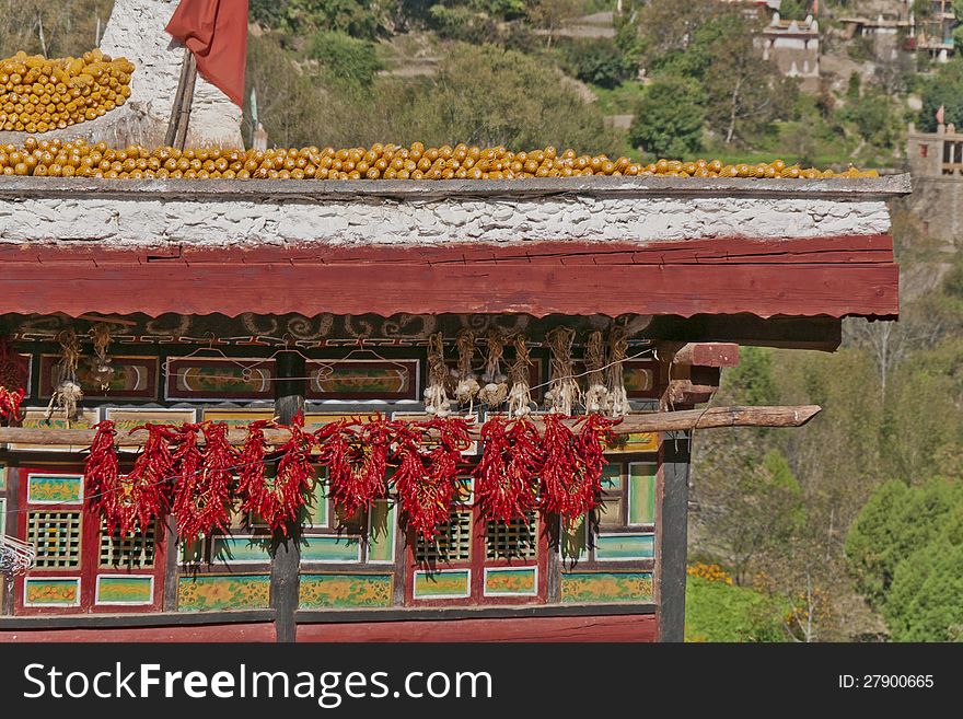 Corns and red peppers are dried under the sun on the roof of a Tibetan folk house