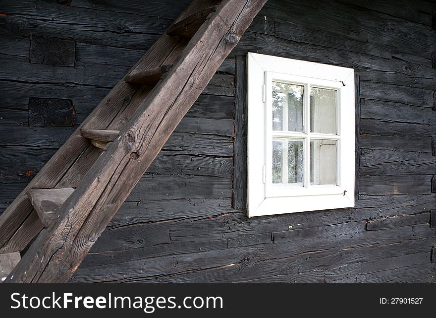 Facade of the frame house with window and ladder to the attic. Facade of the frame house with window and ladder to the attic