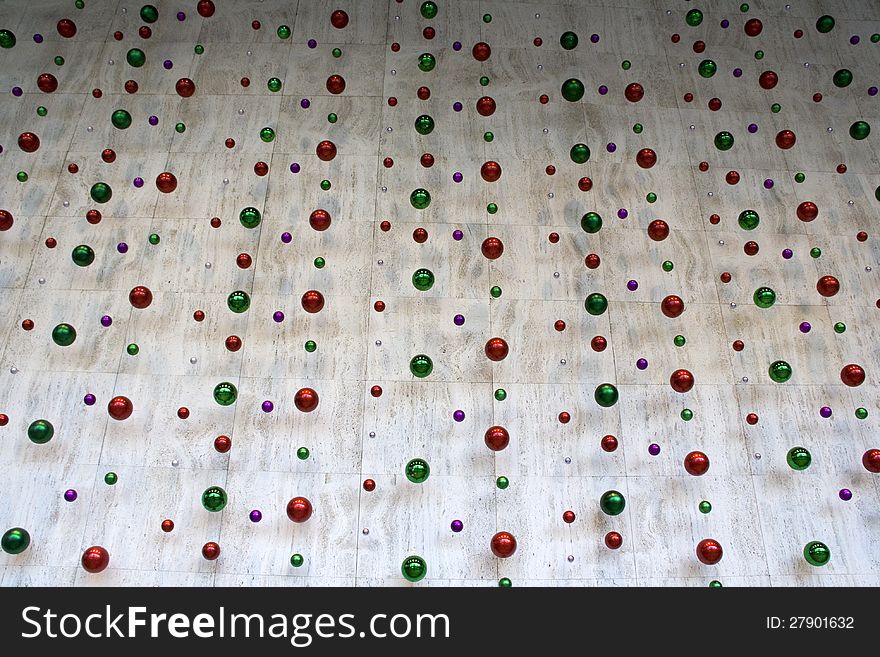 Colorful Christmas balls hanging in front of wall in business building. Colorful Christmas balls hanging in front of wall in business building