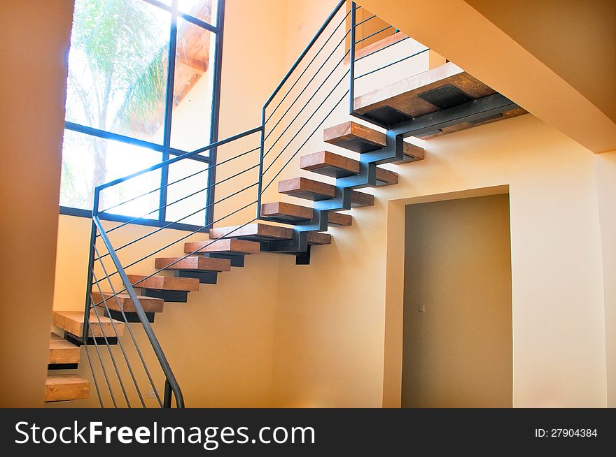 Wooden staircase in a newly built house photographed against a large window. Wooden staircase in a newly built house photographed against a large window