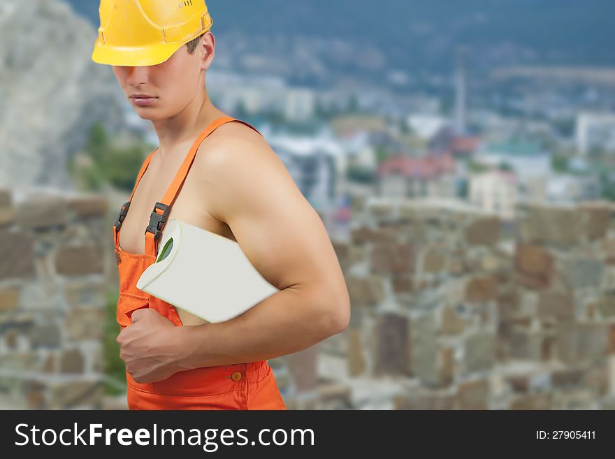 Portrait of a strong builder handsome in protective helmet holding papers in hand over artistic background. Portrait of a strong builder handsome in protective helmet holding papers in hand over artistic background